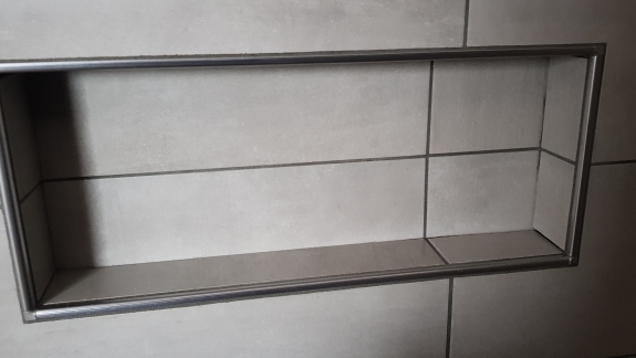 Flisearbejde med indbygget hylde i flisevæg på Salling