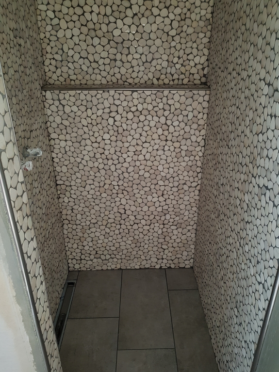 Flisearbejde med naturstensmosaik og bænk i bruseområde i Spøttrup