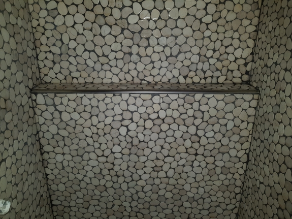 Flisearbejde med naturstensmosaik og integreret hylde i Spøttrup